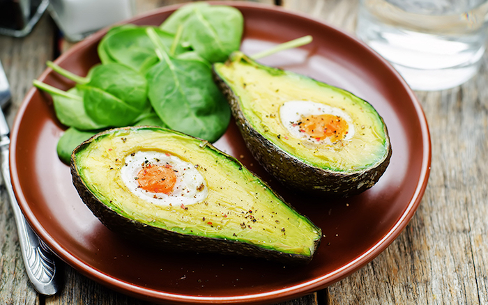 kalorienarmes frühstück, ein brauner teller, avocado mit eiern, grüner salat früstücken