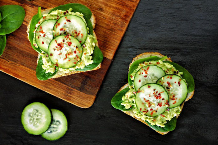 kalorienarmes frühstück mit gemüsen, brotscheiben mit grünem salat, gurken und avocadopüree
