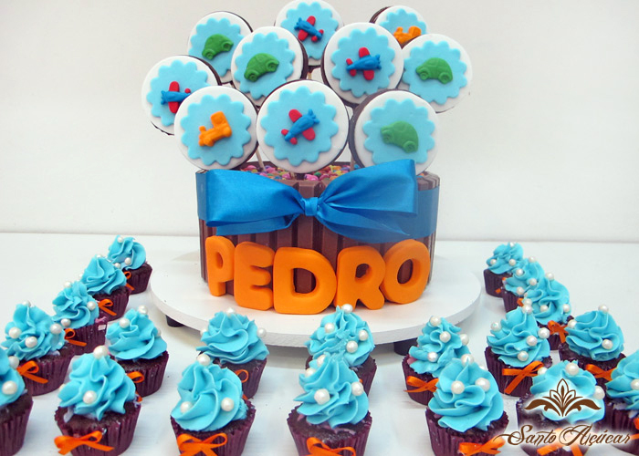 kinderriegel kuchen dekoriert mit bonbons und lutschern aus fondant, cupcakes dekoriert mit blauer buttercreme und zuckerperlen