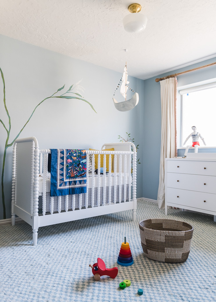 Babyzimmer in Weiß und Hellblau, Spielzeuge aus Holz auf dem Boden, weiße Möbel