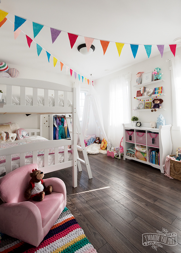 Babyzimmer in fröhlichen Farben, bunte Girlanden aus Papier, weißes Bett und Zelt