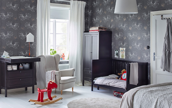 Babyzimmer in Grau, Tapete mit Blumenmuster, rotes Holzpferd, schwarze Möbel