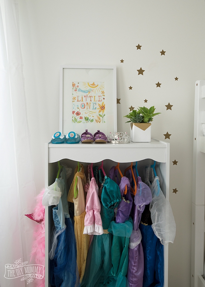 Kleiderschrank im Kinderzimmer, bunte Kinderkleider und Schuhe, grüne Pflanzen und Sternchen an der Wand