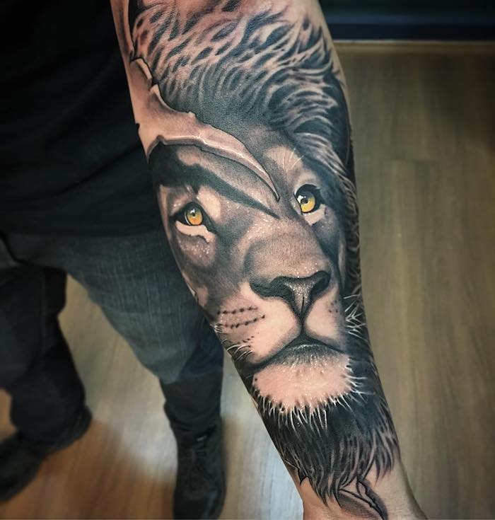 realistisches löwen tattoo am unterarm, löwe mit orangen augen, schwarz-graue 3d-tätowierung