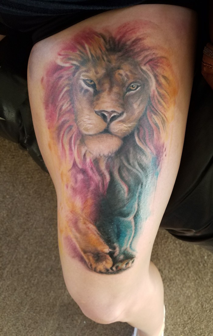 löwenkopf tattoo am bein, wasserfarben, farbige tätowierung mit löwen-motiv, oberschenkel