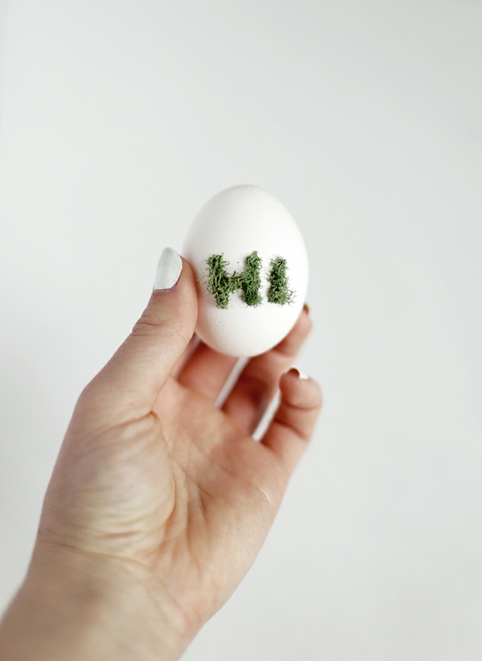 das Wort Hi auf einem Ei mit Moos geschrieben, Ostereier anmalen