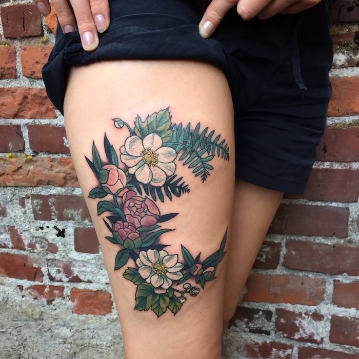 oberschenkel tattoo mit blumen motiv, kurze schwarze hose, blüten in verschiedenen farben, frau