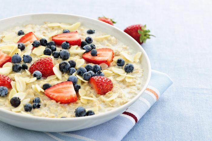 porridge rezept kalorienarm, großer weißer teller, müsli mit milch und obst, vitaminreiches essen