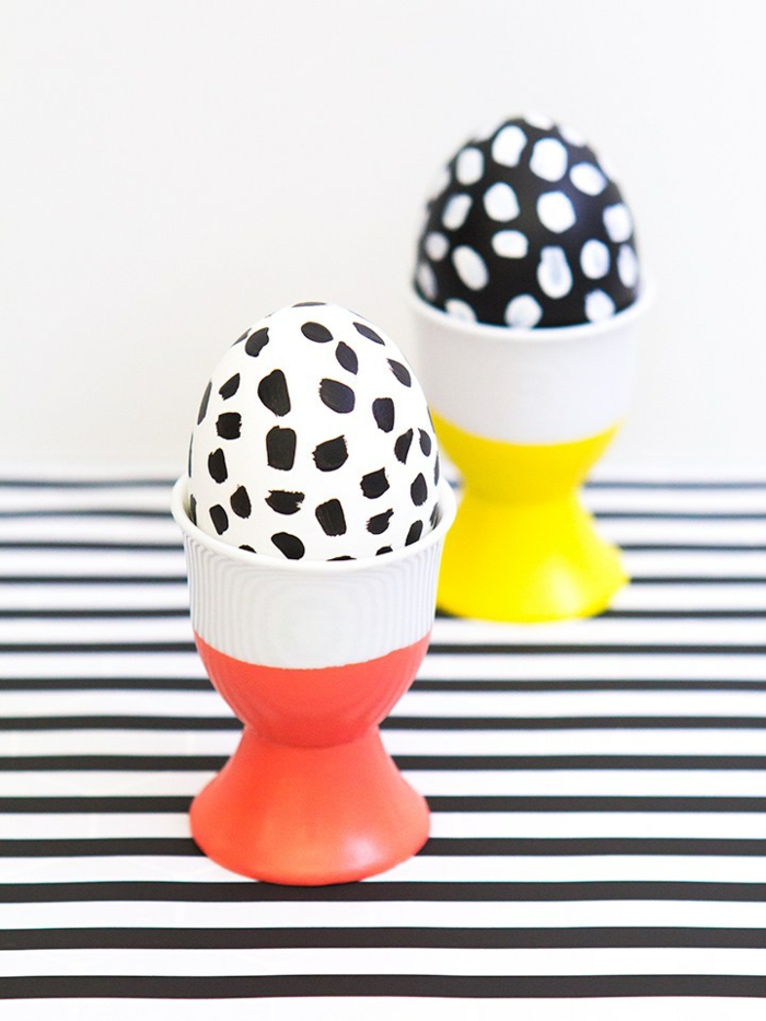 Ostereier dekorieren, zwei Eier in einem roten und einem gelben Becher