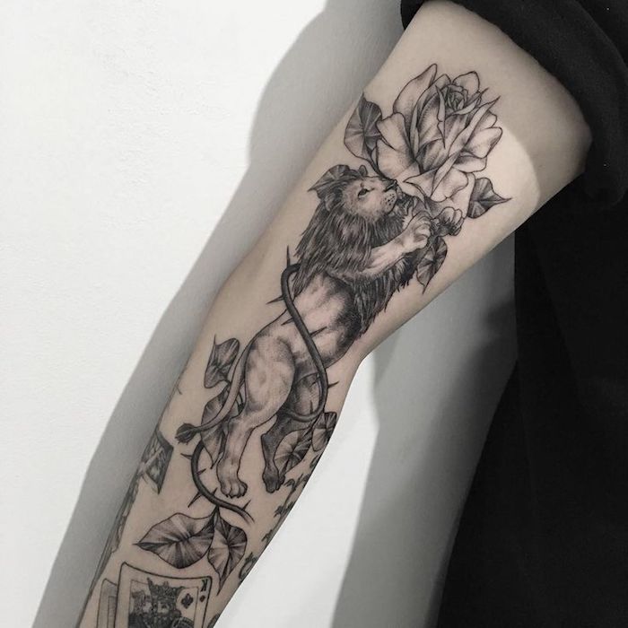 tattoo löwe, schwarz-graue tätowierung mit löwe und weißen rosen, arm tätowieren