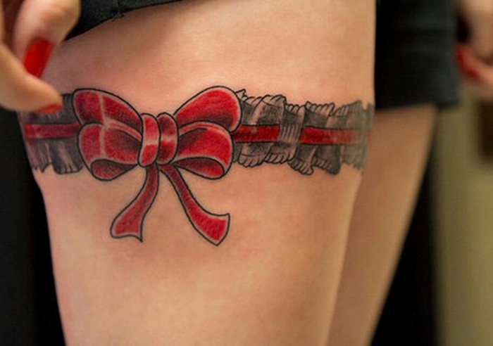 tattoo strumfband, roter nagellack, rote schleife, bein, frau mit tätowierung am oberschenkel