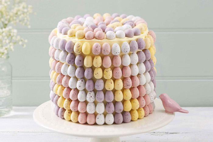 torte kinderschokolade, kuchen für ostern dekoriert mit vielen kleinen eiern, rosa vogel