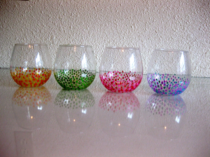 vier bunte Gläser, mit Wattenstäbchen Glas farben in grüner, oranger, rosa und blauer Farbe,