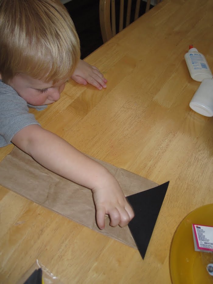 ein kleines kind und eine große tüte aus einem alten papier, basteln mit kindern, eulen basteln und papiertüten falten 
