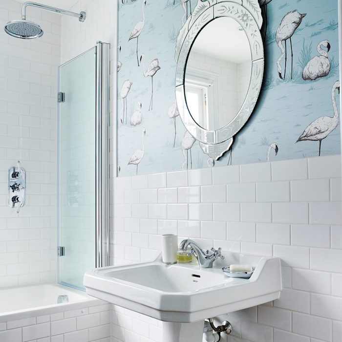 Badezimmer in Weiß und Himmelblau, runder Spiegel mit silbernem Rahmen, weißes Waschbecken