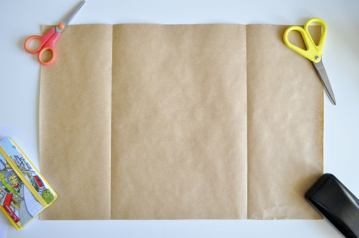 eine kleine pinke schere und ein großes braunes altes blatt papier, basteln mit papier, eine kleine gelbe schere, papiertüten basteln ohne kleben