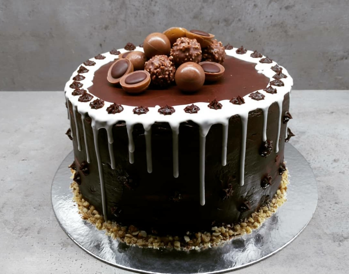 eine Torte mit Schokolade Glasur, drei Arte von Praline als Dekoration, Toffifee Torte