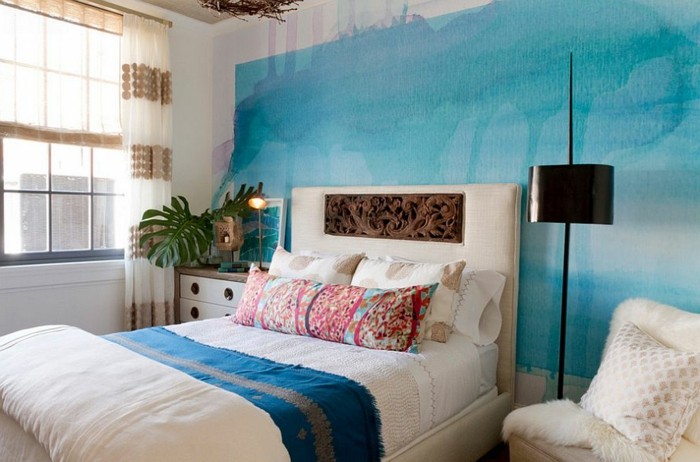 Wohnzimmer Einrichtung, Wandfarbe Blau, weißes Bett, schwarze Stehlampe, Kissen mit Blumenmuster