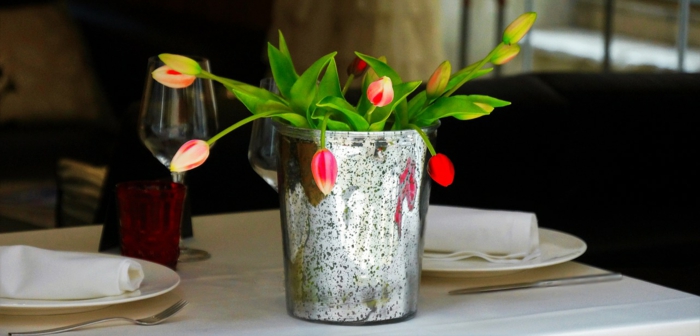 kleine rote Blumen, eine silberne Vase, eine weiße Tischdecke, Tischdeko Kommunion