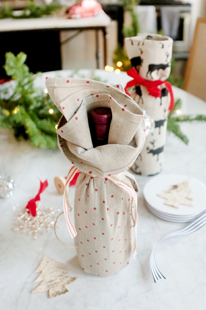 Flasche als Geschenk verpacken, graues Tuch auf kleine rote Flecken, Geschenk zu Weihnachten