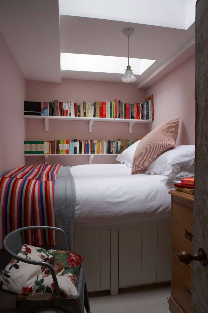 bunte Decke, verschiedene bunte Bücher, ein kleines Bett, ein Regal aus Holz