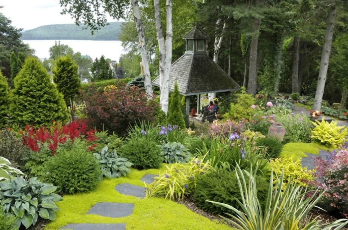 ein harmonischer Garten, grünes Grass, Beete mit bunten Blumen, ein Gartenpavillion, Garten anlegen günstig