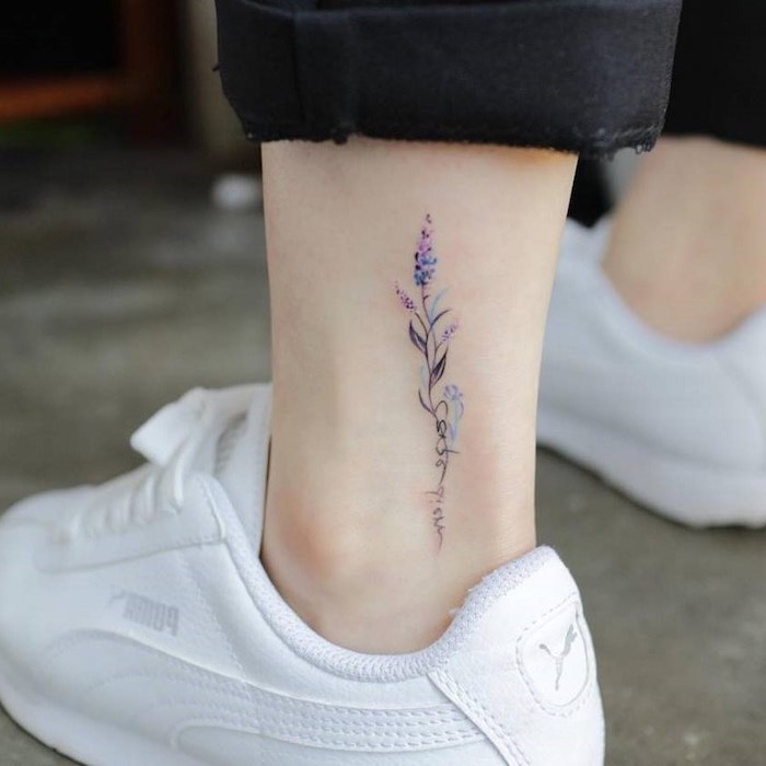 Zartes Knöchel Tattoo für Frauen, kleine lila Blume, weiße Sneaker und schwarze Hose