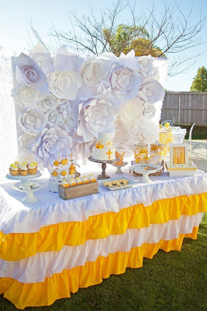 eine Torte mit Kreuz, weiße und gelbe Tischdecke, Papierblumen, Kommunion Tischdekoration