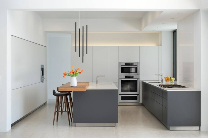 eine minimalistische Küche, Wandfarbe Hellgrau, Kochinsel und Theke, weißer Bodenbelag