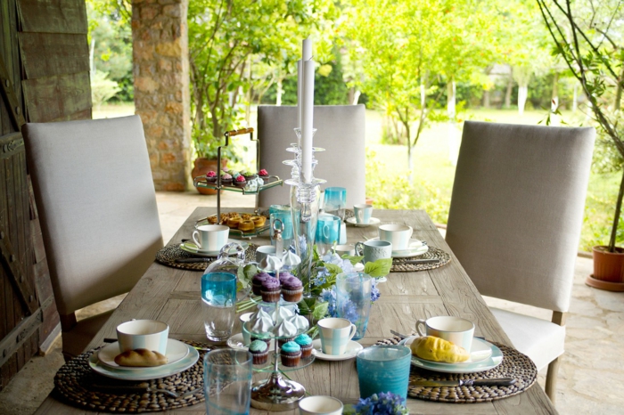 Kommunion Dekoration, drei graue Stühle, Tisch aus Holz, Cupcakes und Kerzen