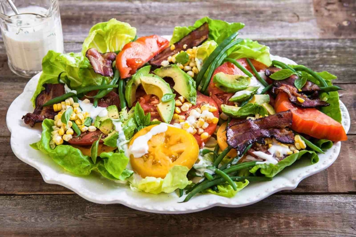 gesunde Salate, Kirschtomaten, Avocado, mit weißen Dressing bedeckt