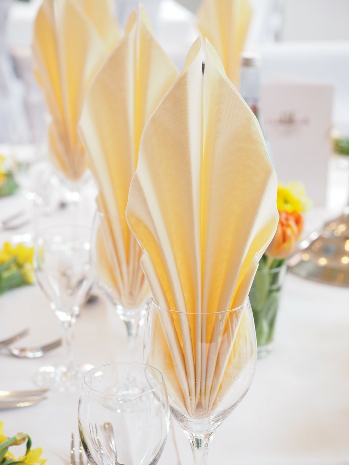 orange Servietten Kommunion, kleine Tulpen in Vasen, weiße Tischdecke