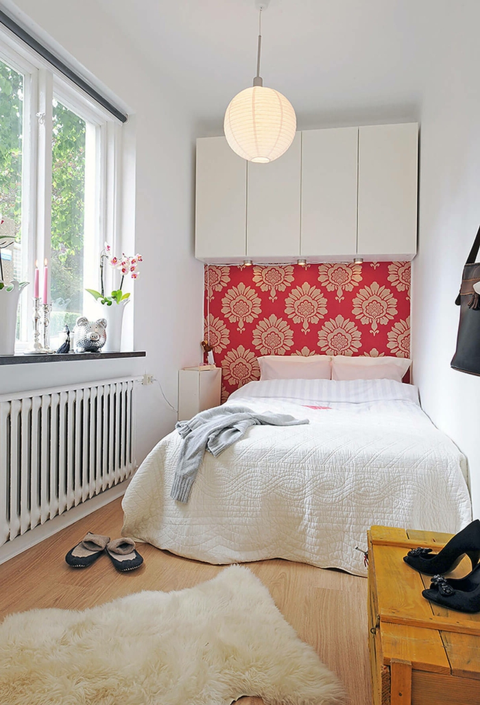 ein kleines Schlafzimmer für zwei, ein weißes Bett, rote Tapete mit Blumenmuster, kleine Räume optisch größer wirken