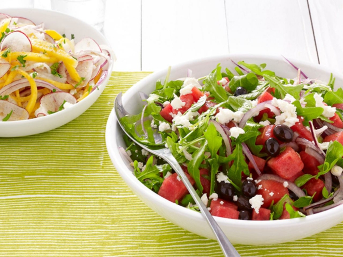 Rucola, rotes Gemüse, Oliven, Käse, gesunde Salate in einer weißen Schale