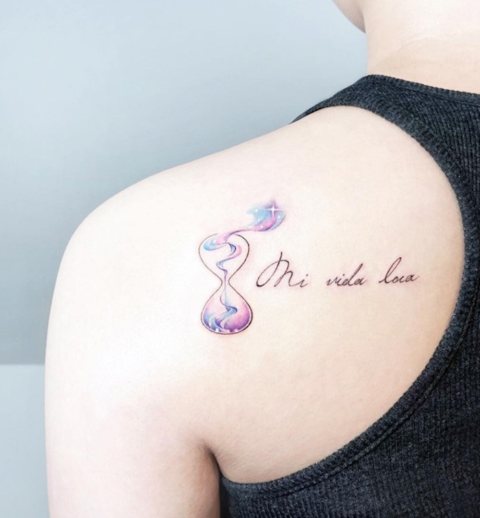 mensch mit einem schulterblatt mit einem kleinen winzigen farbigen watercolor tattoo mit einer kleinen violetten sanduhr mit vielen kleinen und großen weißen sternen, tattoo sanduhr bedeutung 