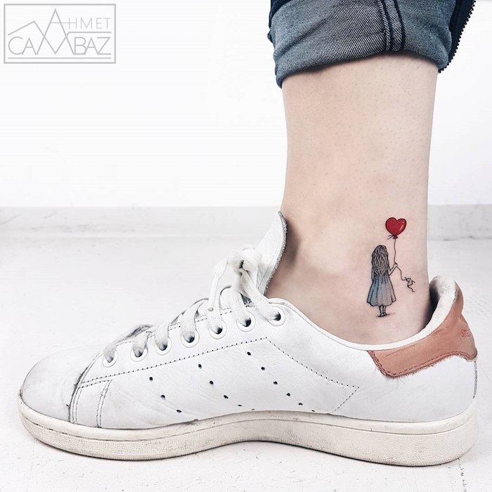 Kleines Tattoo am Knöchel, Mädchen mit blauem Kleid und schwarzen langen Haaren hält roten Herz-Ballon, weiße Sneaker