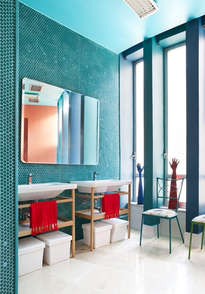 Badezimmer in Türkis, großer Spiegel, weiße Waschbecken, rote Tücher