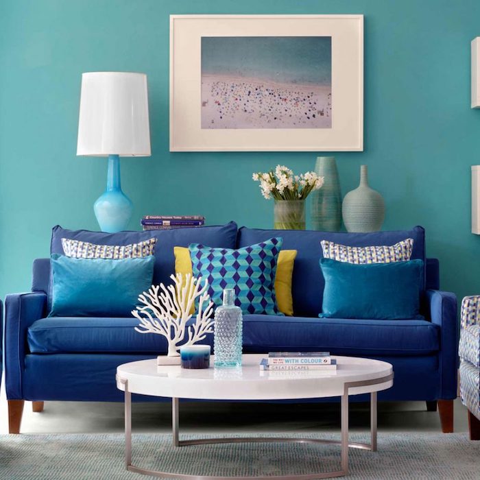 Wohnzimmer Einrichtung in Blautönen, Wandfarbe Türkis, dunkelblaues Sofa, weißer runder Couchtisch