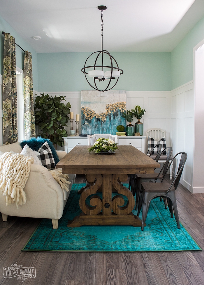 Wohnzimmer im Landhausstil, Tisch aus Massivholz, runder Kronleuchter, grüne Zimmerpflanzen, Kombination aus Blaugrün und Weiß