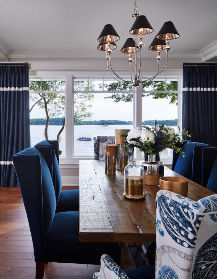 Wohnzimmer in Dunkelblau und Weiß, Tisch aus massivem Holz, blaue Vorhänge und Stühle