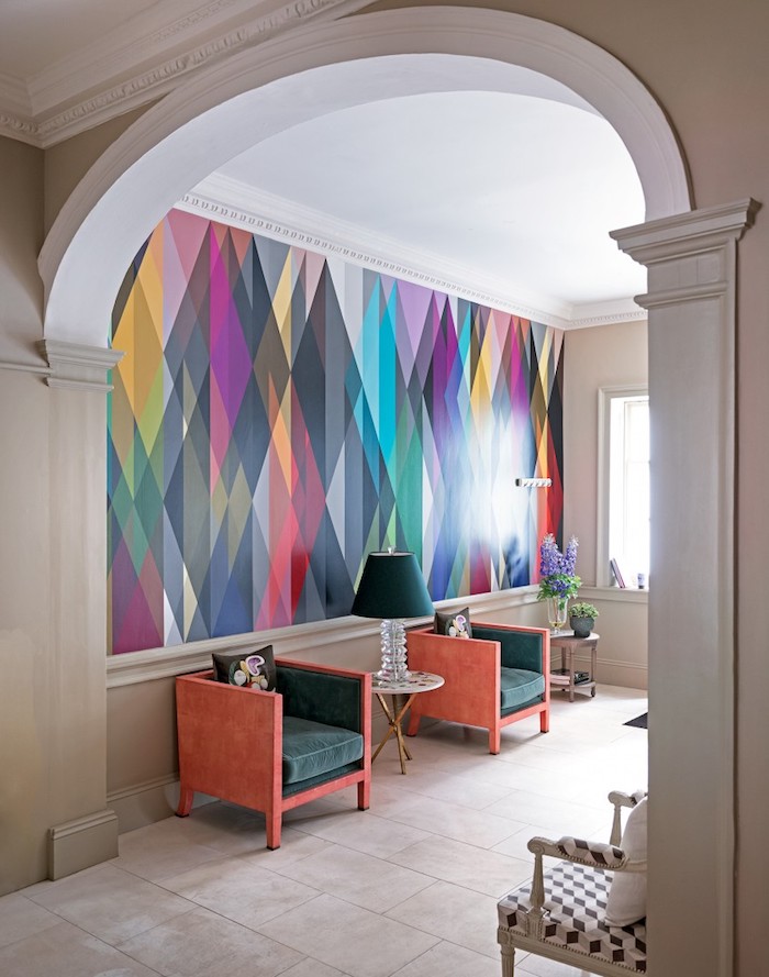 Wand in Regenbogenfarben, Stühle in Dunkelgrün und Koralle, weiße Fliesen