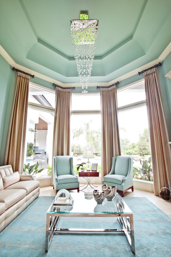 Wohnzimmer in Pastellfarben, Wandfarbe Blaugrün, Vorhänge in creme, Glas Couchtisch, Kronleuchter mit Kristallen
