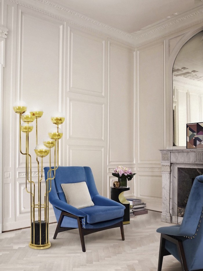 Wandfarbe Weiß, blaue Sessel, Kamin und großer Spiegel, goldene Stehlampe