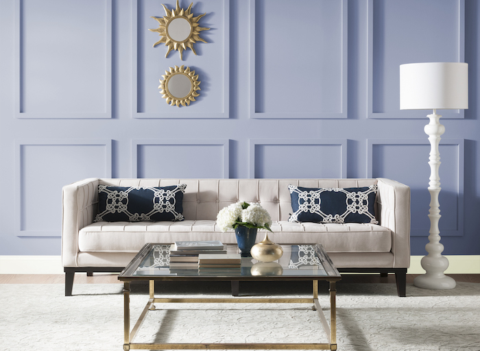 Kombination aus Blau und Weiß, Spiegel in Form von Sonnen, weißes Sofa mit dunkelblauen Deko Kissen, weiße Stehlampe 