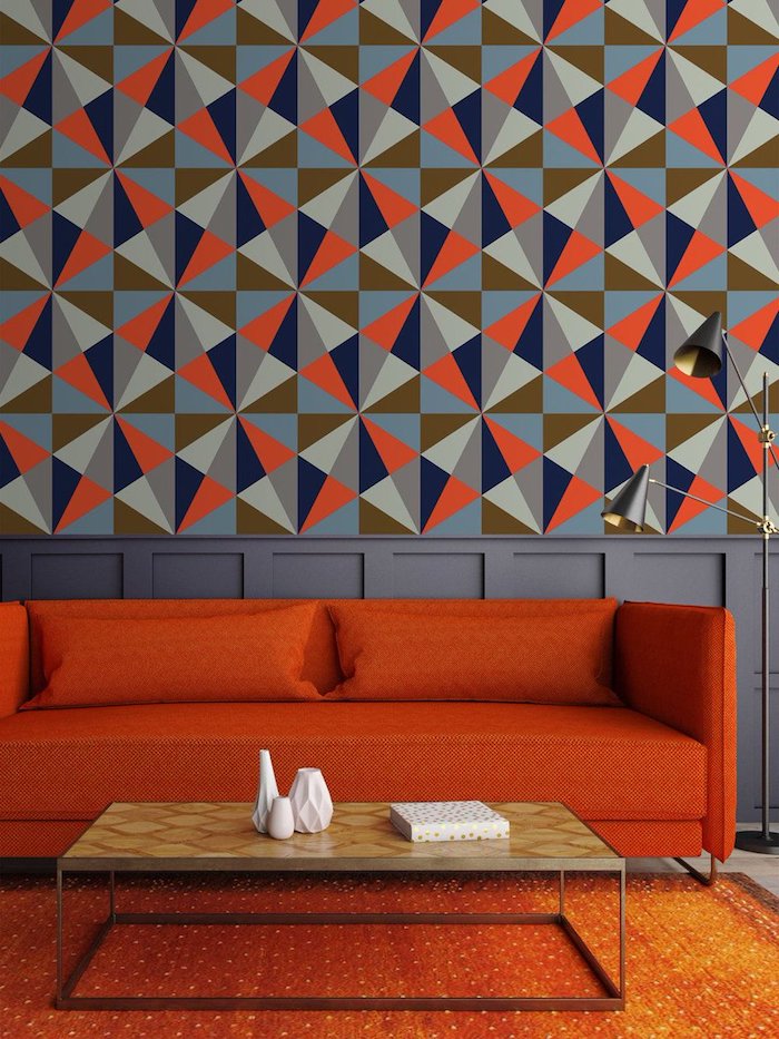Tapete mit geometrischen Formen, rotes Sofa und niedriger Holztisch, kleine weiße Porzellanvasen