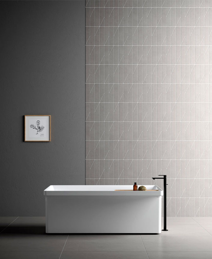 Badezimmer Einrichtung, schlichtes Design, graue Wand- und Bodenfliesen, weiße Badewanne