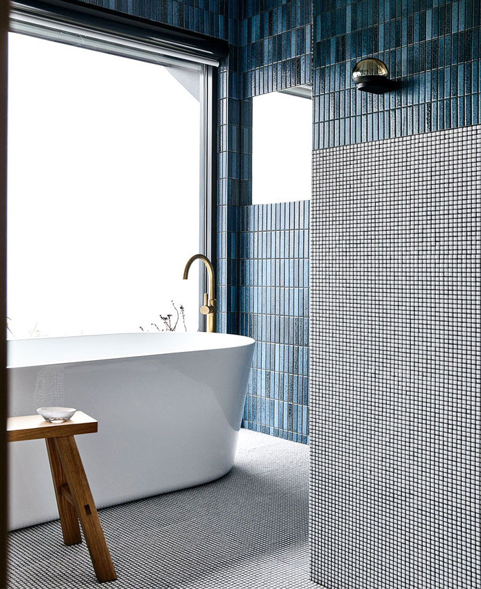 Badezimmer Einrichtung, weiße Badewanne, großes Fenster, dunkelblaue und graue Fliesen