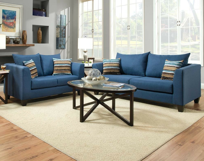 Blaue Sofas, ein rundes Tischlein aus Glas, ein weißer Teppich, Wohnideen Wohnzimmer
