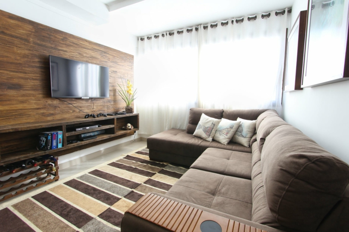 ein braunes Sofa, brauner Teppich, Fernsehwand ais Holz, Wohnzimmergestaltung