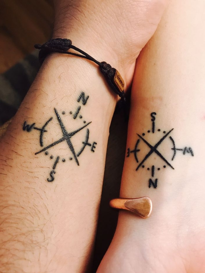 zwei hände mit kleinen schwarzen compass tattoos mit schwarzen pfeilen und kleinen armbändern aus leder, tattoo am handgelenk, ein winziger partnertattoo